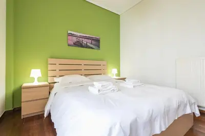 a bedroom with a white bed and a green wall at Glyfada Glass-Walled Designed Apt 1Gbps in Athens