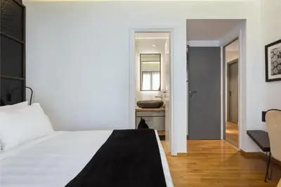 a bedroom with a white bed and a bathroom at Acropolis Unique Residence in Athens