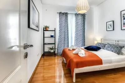 a bedroom with a bed with orange sheets and a window at Spacious apartment in Glyfada close to the sea in Athens