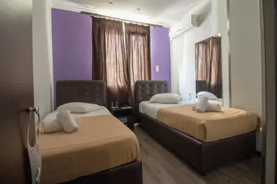 two beds in a room with purple walls at Cosmopolit in Athens