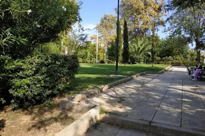 two people sitting on a bench in a park at Psychiko's View in Athens