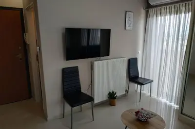 a living room with two chairs and a television on a wall at Psychiko's View in Athens