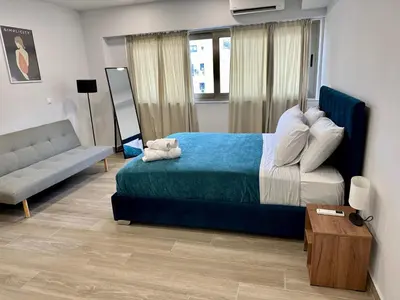 a bedroom with a blue bed and a couch at Academys Modern Apartments by Athens Urban Retreat in Athens