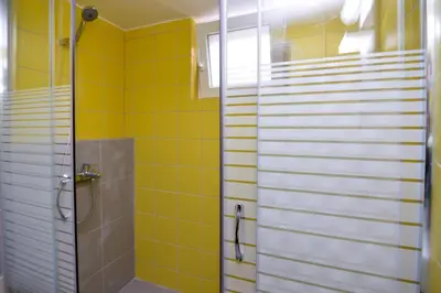a bathroom with a shower and yellow tiles at Athens Sea view 2 floor apartment next to Marina in Athens