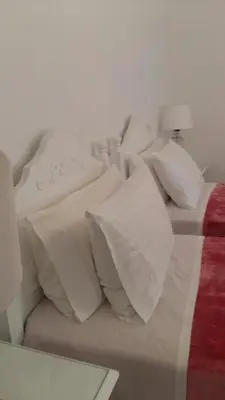 a white bed with white pillows and a red blanket at NN Spata Rooms & Suites near Athens airport in Spáta