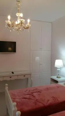 a bedroom with a red bed and a chandelier at NN Spata Rooms & Suites near Athens airport in Spáta