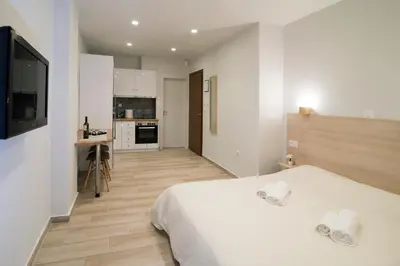 a bedroom with a white bed and a kitchen at Lovely central studio! in Athens