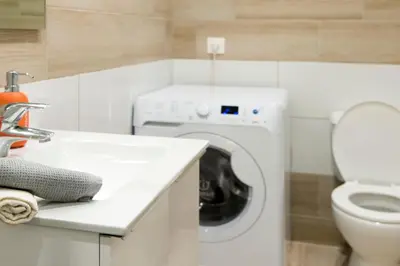 a white bathroom with a washing machine and a sink at Lovely central studio! in Athens