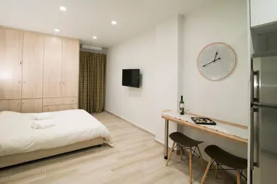 a bedroom with a bed and a desk and a clock at Lovely central studio! in Athens