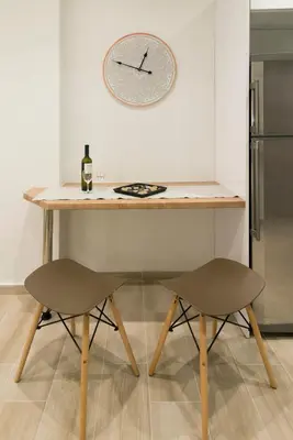 a table with two chairs and a clock on the wall at Lovely central studio! in Athens