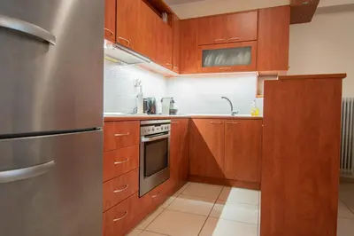 a kitchen with wooden cabinets and a stainless steel refrigerator at Homey Penthouse in Kypseli in Athens