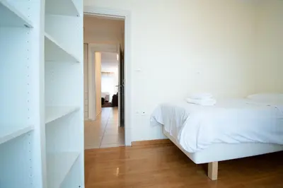 a white bedroom with a bed and a hallway at Homey Penthouse in Kypseli in Athens