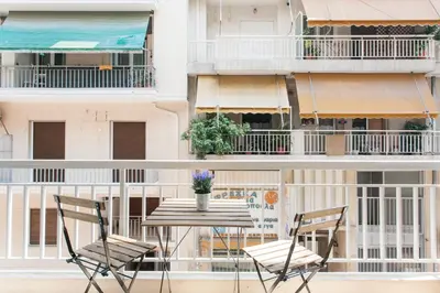a table and chairs on a balcony with a building at Cozy, Central, Safe apartment close to Acropolis in Athens