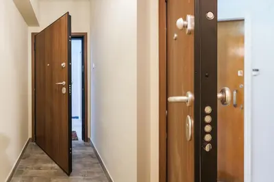a hallway with two wooden doors and a mirror at Museum of Modern Apartment next to Suggrou Fix metro- big, safe, simple and central in Athens