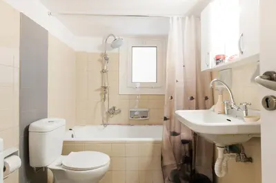 a white bathroom with a toilet and a sink at Museum of Modern Apartment next to Suggrou Fix metro- big, safe, simple and central in Athens