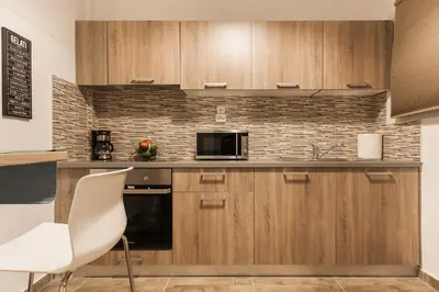 a kitchen with wooden cabinets and a microwave at Museum of Modern Apartment next to Suggrou Fix metro- big, safe, simple and central in Athens