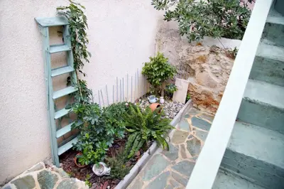 a garden next to a pink building with plants at Aroura Homes Garden House 2BR 2BA Free Parking in Athens
