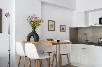 a kitchen with a table with white chairs and a vase of flowers at The Square Six in Athens