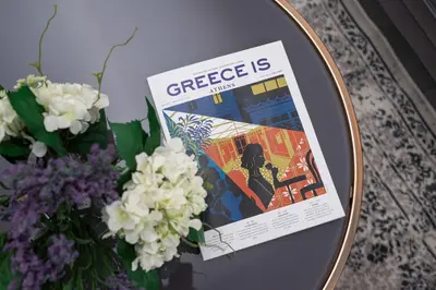 a magazine sitting on a table next to a vase of flowers at The Square Six in Athens