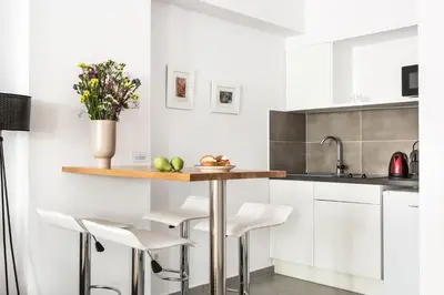 a kitchen with white cabinets and a counter with stools at The Square Six in Athens