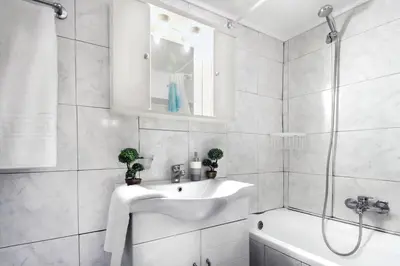 a white bathroom with a sink and a shower at Gazi apartment with Acropolis views in Athens