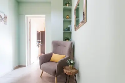 a gray chair with a yellow pillow in a room at A Modern Antique Central 3 Bedroom Simple Apartment near to Acropolis in Athens