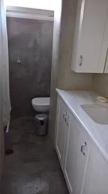 a white bathroom with a toilet and a sink at Under the Acropolis, tiny room, big terrace in Athens