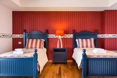 a bedroom with two beds and a red wall at Amazing 5 bedroom Villa with Swimming Pool in Athens