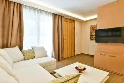 a living room with a white couch and a television at Modern hospitality, with private garden, Athens in Athens