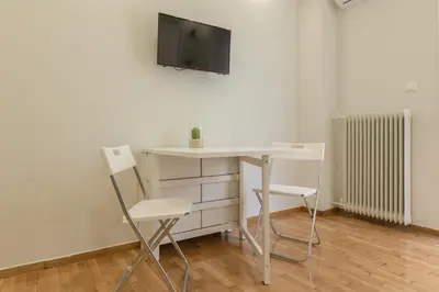 a desk with two chairs and a tv on a wall at Cozy Flat with Terrace & Patio, next to Lycabettus in Athens