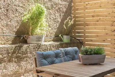 a wooden bench sitting next to a wall with two potted plants at Cozy Flat with Terrace & Patio, next to Lycabettus in Athens