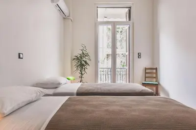 two beds in a white room with a window at Neoclassical Apartment near Acropolis - LivingStone Crystal in Athens