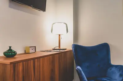 a blue chair sitting next to a desk with a lamp at Neoclassical Apartment near Acropolis - LivingStone Crystal in Athens