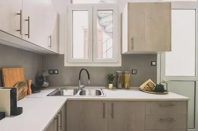 a kitchen with white cabinets and a sink at Neoclassical Apartment near Acropolis - LivingStone Crystal in Athens