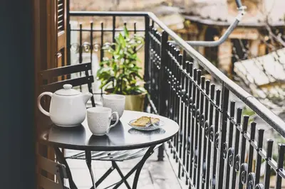 a table with cups and a plate of food on a balcony at Neoclassical Apartment near Acropolis - LivingStone Crystal in Athens