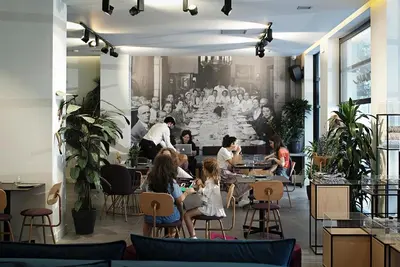 a group of people sitting at tables in a restaurant at The Gem Society Hotel in Athens