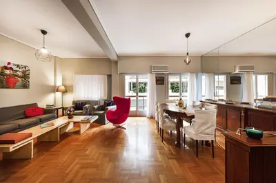 a kitchen and living room with a table and red chairs at Spacious 3 Bedroom apt near Acropolis museum in Athens