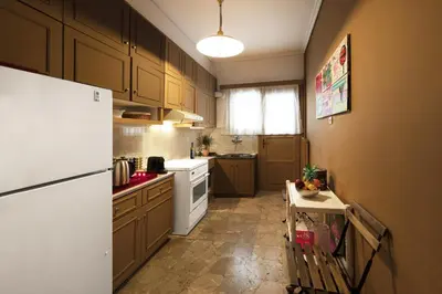 a kitchen with wooden cabinets and a white refrigerator at Spacious 3 Bedroom apt near Acropolis museum in Athens