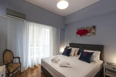 a bedroom with a bed with blue walls and a window at Spacious 3 Bedroom apt near Acropolis museum in Athens