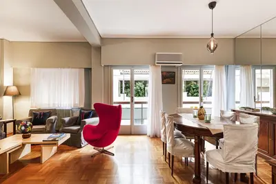 a living room with a table and a red chair at Spacious 3 Bedroom apt near Acropolis museum in Athens