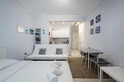 a white room with two beds and a table at Beautiful studio at Panathenaic Stadium in Athens