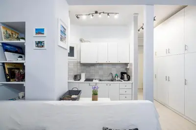a white kitchen with white cabinets and a table at Beautiful studio at Panathenaic Stadium in Athens