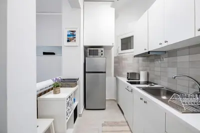 a white kitchen with a sink and a refrigerator at Beautiful studio at Panathenaic Stadium in Athens