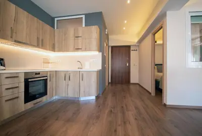 a kitchen with wooden cabinets and a living room at Abstract Flat With Urban View in Athens