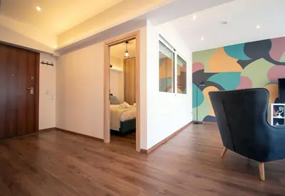 a living room with a chair and a bedroom at Abstract Flat With Urban View in Athens