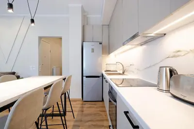 a kitchen with white counter tops and chairs at The Flirty Athens apartment in Athens