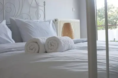 a white bed with towels on top of it at Glyfada A Modern minimal apartment in Athens