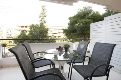 a glass table and chairs on a balcony at Glyfada A Modern minimal apartment in Athens