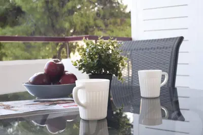 a table with a bowl of apples and two cups at Glyfada A Modern minimal apartment in Athens