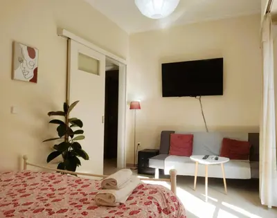 a bedroom with a bed and a couch and a tv at Next to Metro! Bright Apartment with Fully Equipped Kitchen in Athens